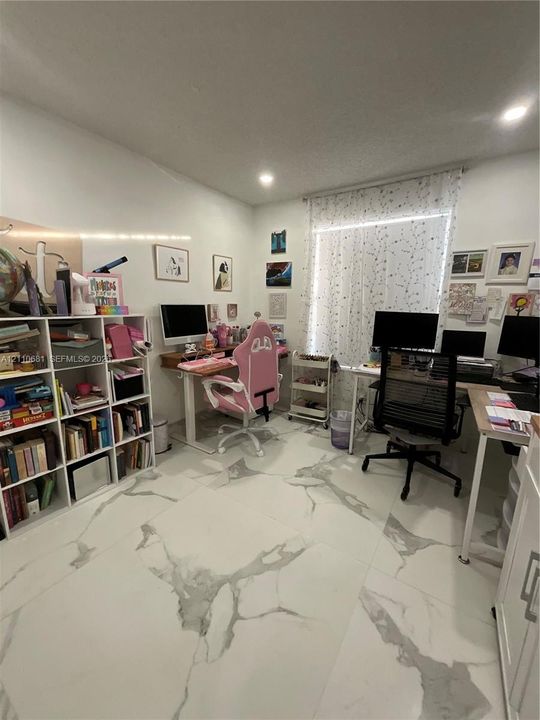 Large-format tile flooring with a neutral veined pattern, recessed ceiling lighting, and built-in white shelving