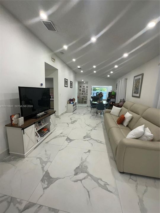 Large-format tile flooring with a veined pattern, recessed ceiling lighting, and smooth-finish walls