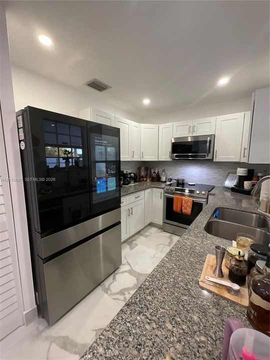 Kitchen featuring white shaker-style cabinetry, stone-finish countertops, stainless steel appliances, a multi-door smart refrigerator, and recessed lighting