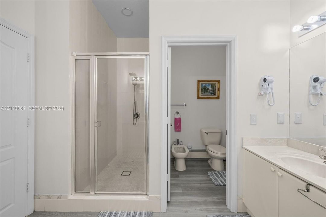 walk-in shower with metal-framed glass enclosure, vanity with integrated basin, bidet, toilet