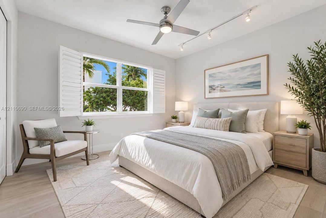 Light-filled room featuring wood-finish flooring, plantation shutters, track lighting, and a brushed metal ceiling fan