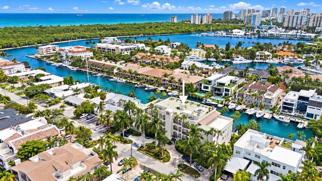 Aerial view showcasing a waterfront community with multiple residences featuring turquoise-water canals, mature palm trees, and lush landscaping throughout the neighborhood