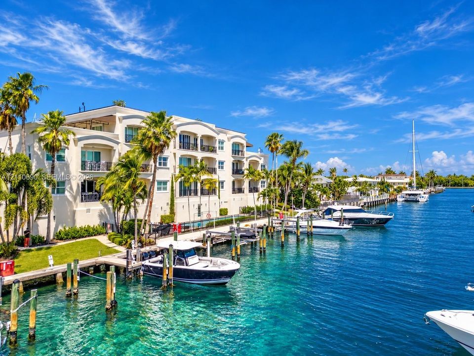 Waterfront residence featuring a three-story white stucco facade with arched windows and multiple balconies