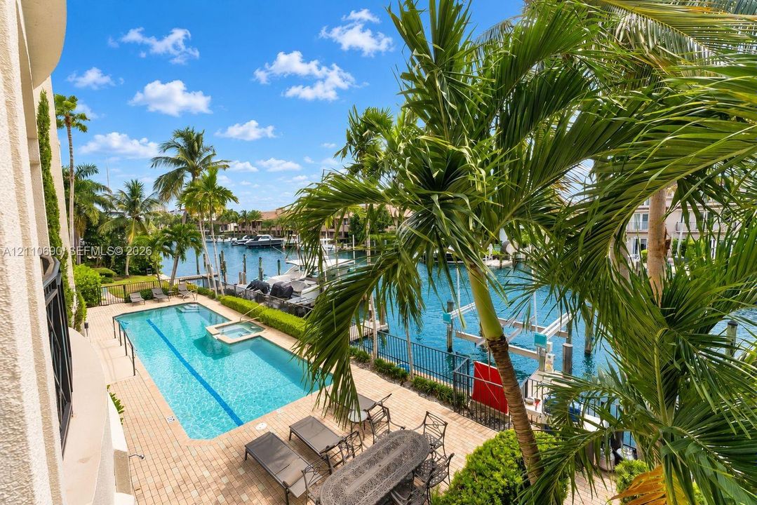 Waterfront outdoor area featuring a rectangular lap pool, integrated spa, brick paver decking, and private boat dockage