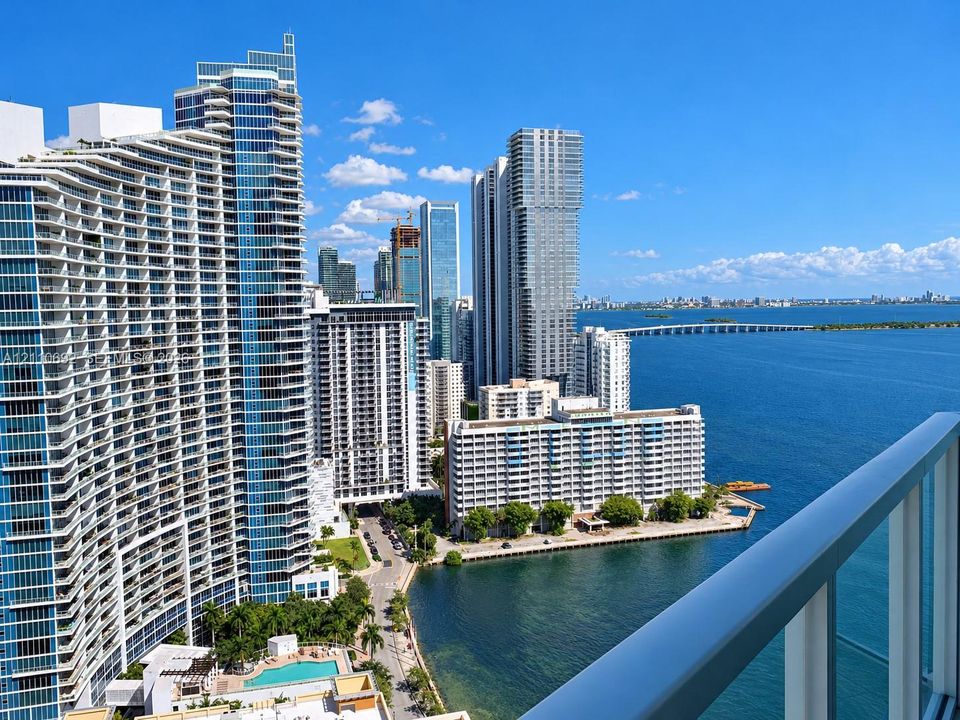 Private balcony featuring a glass and metal railing, overlooking the coastal skyline and harbor