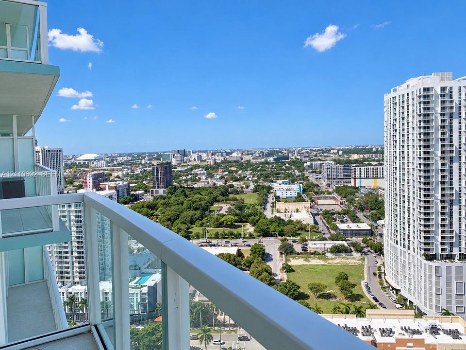 Elevated private balcony featuring glass panel railings and expansive urban scenery