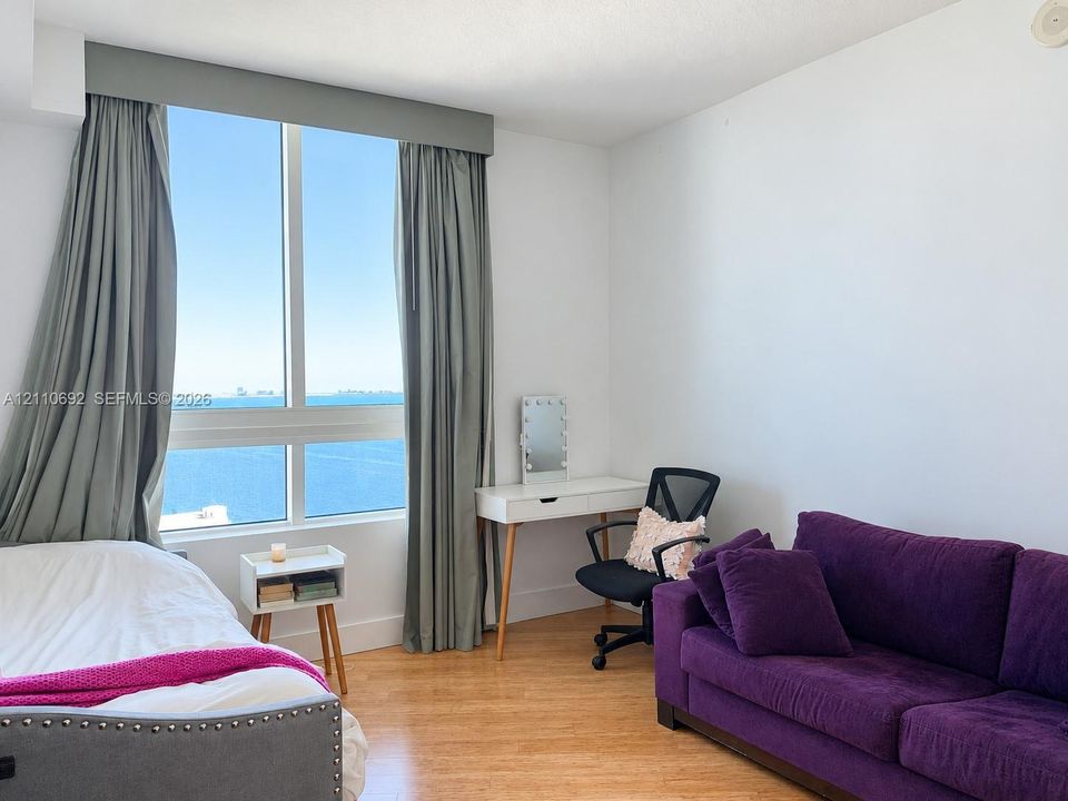 Floor-to-ceiling windows featuring expansive coastal scenery, wood-finish flooring, and a neutral color palette