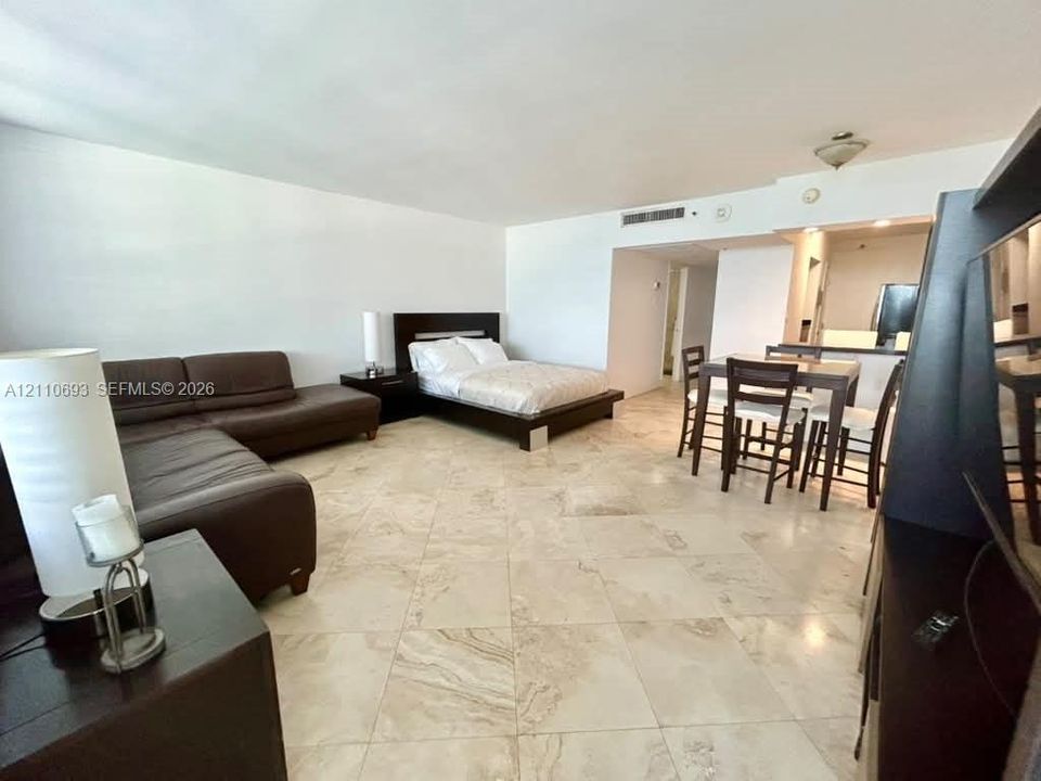 Open-concept interior featuring large-format natural stone flooring, crisp white walls, and a recessed ceiling lighting fixture