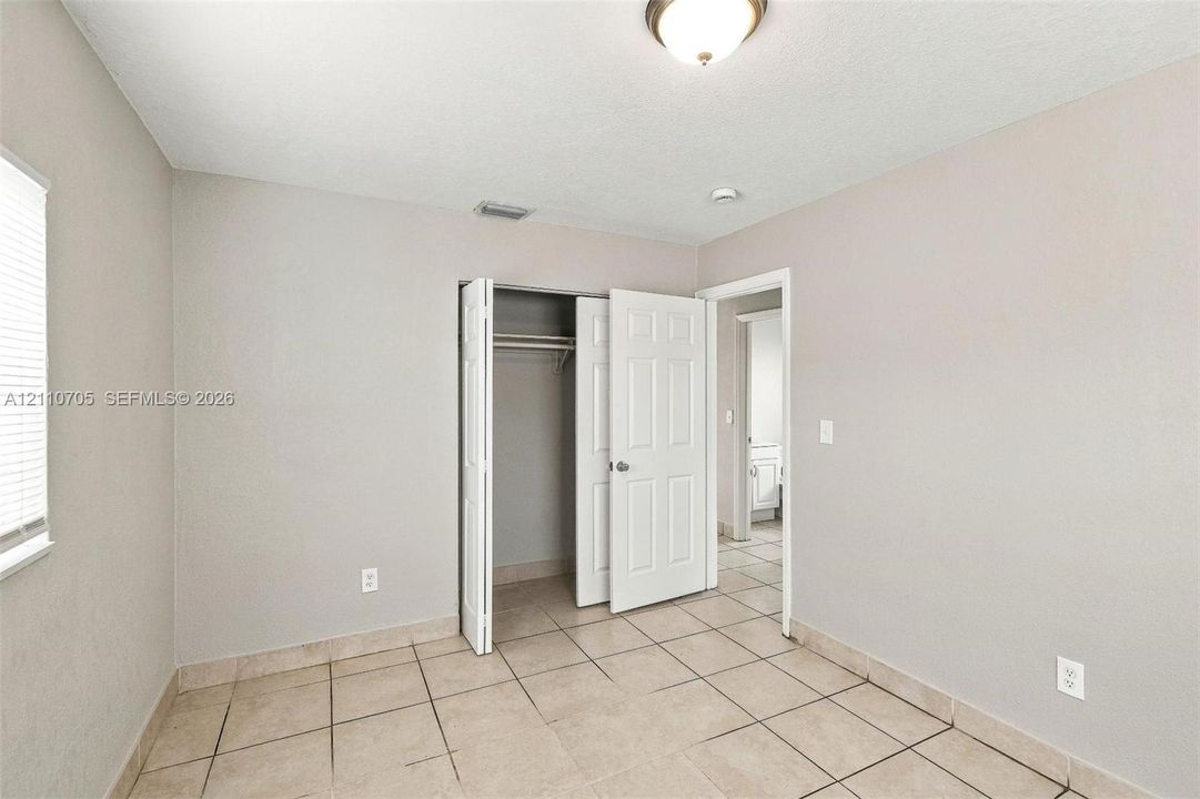 Neutral-toned room featuring tile flooring, six-panel closet doors, and flush-mount ceiling lighting