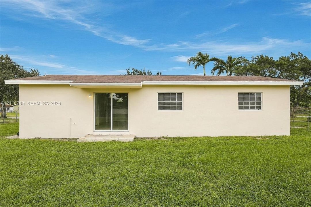 Stucco exterior featuring a low-slope roof, sliding glass patio door, concrete step, and grid-patterned windows