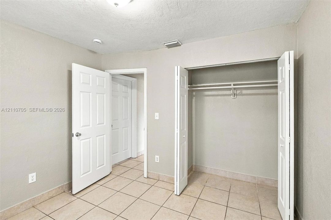 Neutral interior featuring ceramic tile flooring, six-panel interior doors, and a reach-in closet with an integrated rod