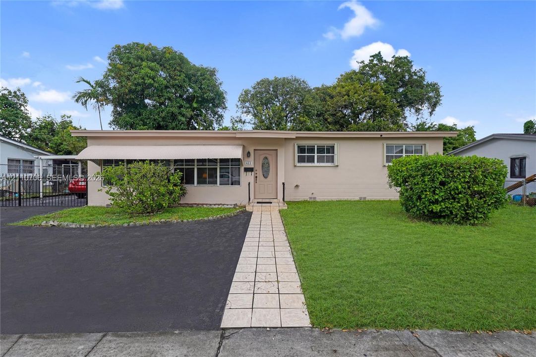 Single-story residence featuring a neutral exterior, an asphalt driveway, a tiled walkway, window awnings, and a landscaped front lawn