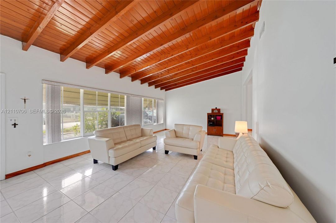 Vaulted exposed wood-beam ceiling, large-format tile flooring, and oversized windows