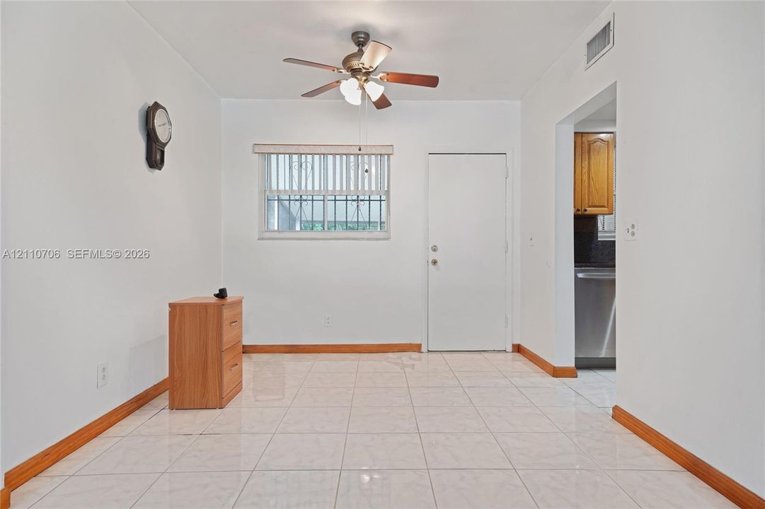 Light-toned tile flooring throughout with wood-trim molding, ceiling-mounted paddle fan with integrated light fixture, and horizontal blind window covering