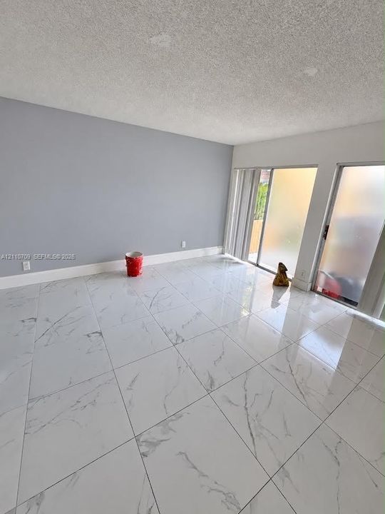 Polished large-format tile flooring with a veined pattern, dual sliding glass doors, and neutral wall tones