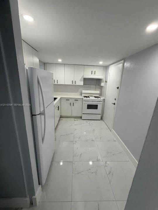 Kitchen featuring white cabinetry, solid-surface countertops, integrated range hood, white appliances, granite counter top