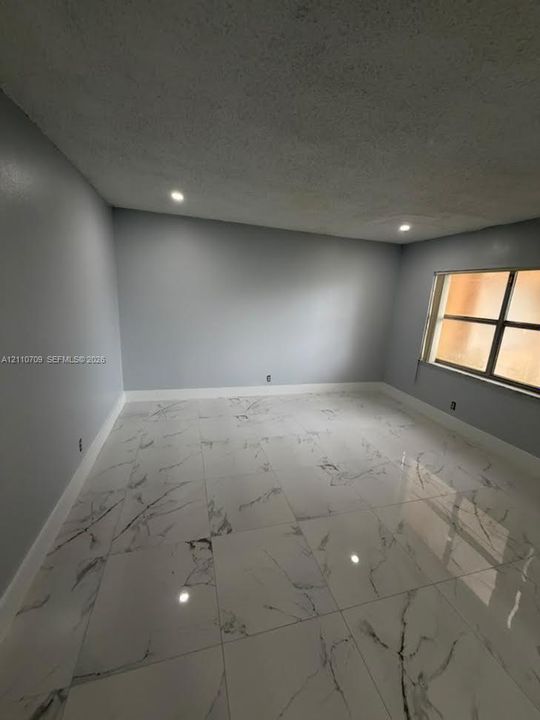 Room featuring large-format stone-patterned tile flooring, neutral grey wall paint, and recessed ceiling lighting