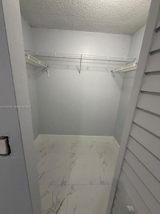 Walk-in closet featuring large-format stone-look tile flooring and white wire shelving