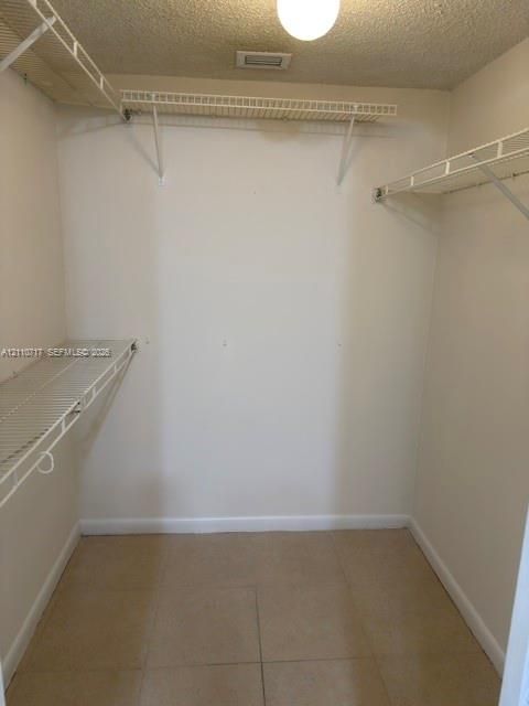 Walk-in closet featuring tiled flooring and tiered white wire shelving