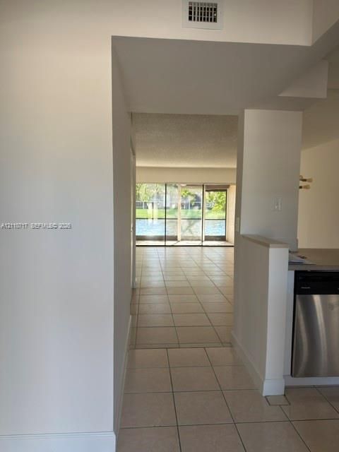 Large ceramic tile flooring, stainless steel dishwasher, and expansive sliding glass doors