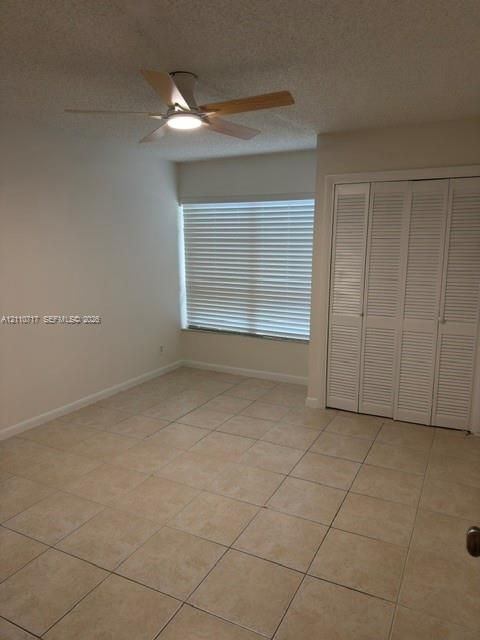 Ceramic tile flooring, white louvered-style closet doors, ceiling fan with integrated lighting, and horizontal window blinds