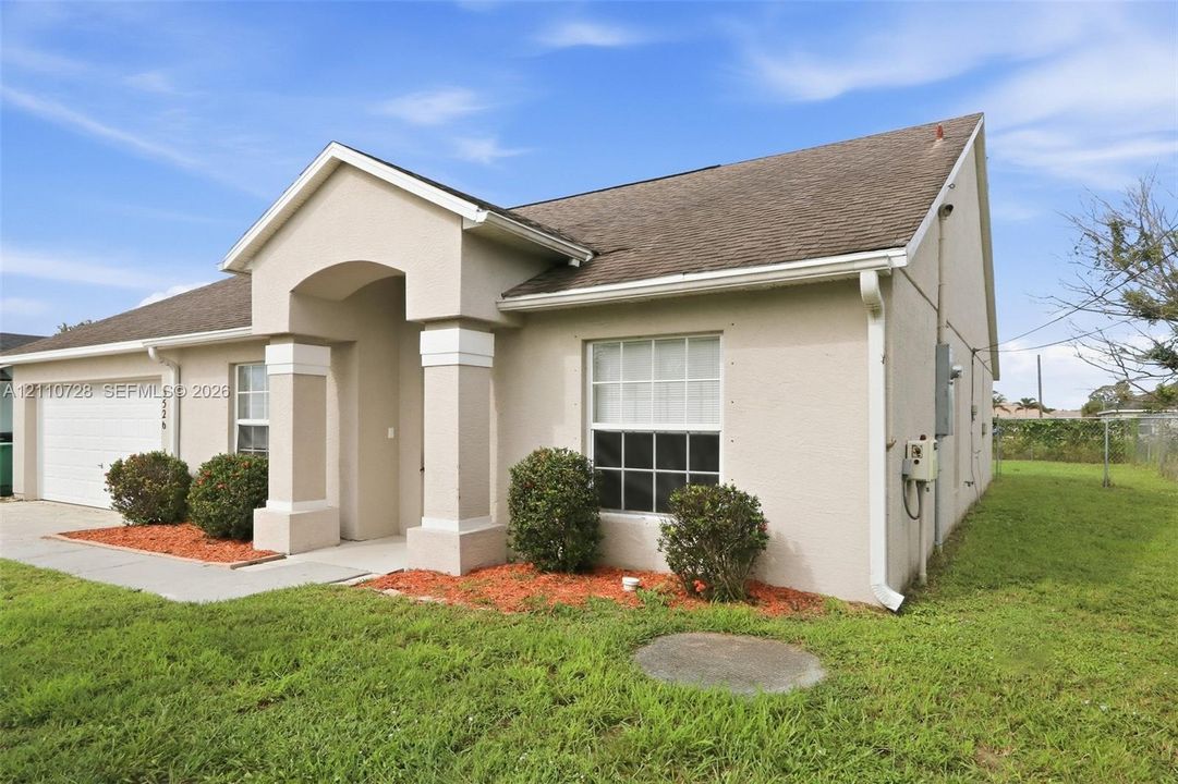 Single-story residence featuring a stucco exterior, arched covered entryway with structural columns, multi-pane windows, and an attached two-car garage