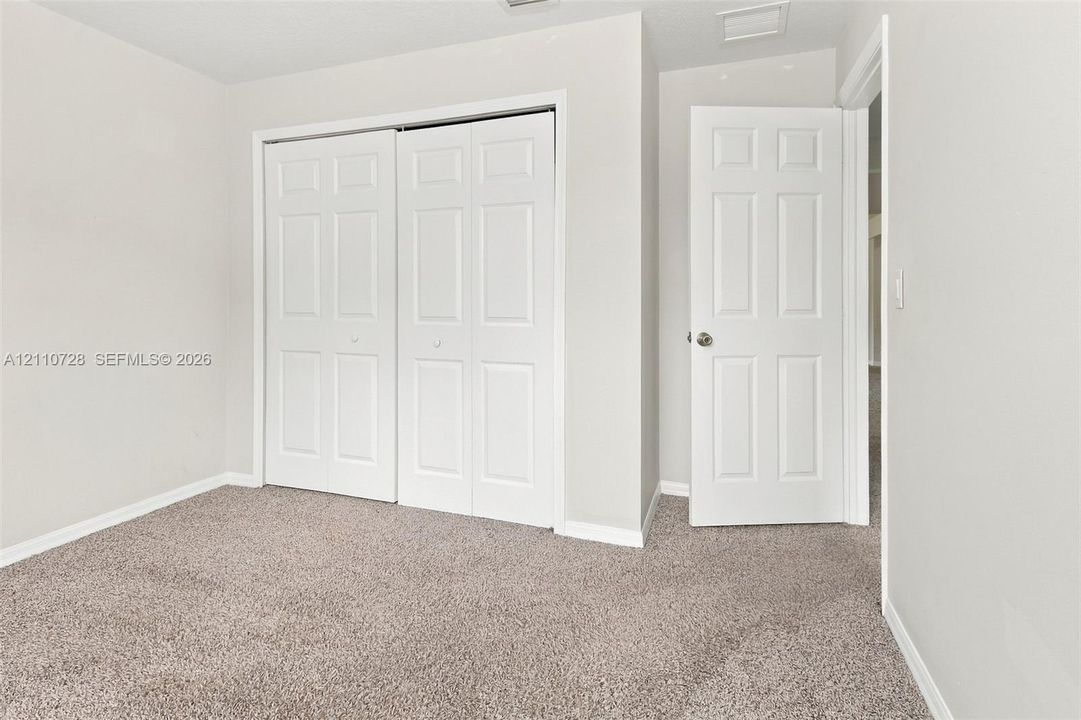 Neutral-toned carpet flooring, multi-panel interior doors, and dual-panel sliding closet doors