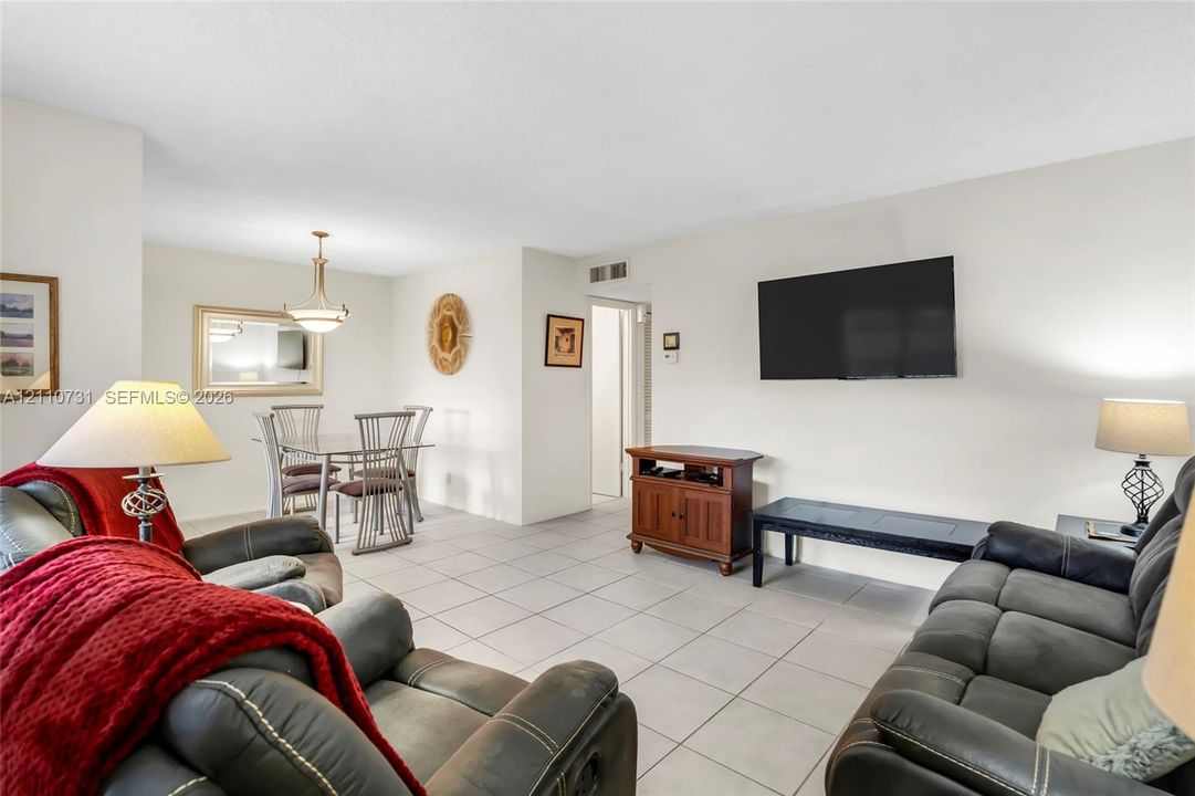 Neutral-toned ceramic tile flooring, built-in wall-mounted light fixture above the dining area, and wall-mounted television console