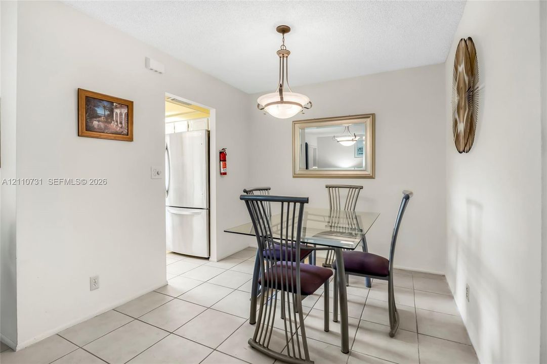 Dining area featuring ceramic tile flooring, a multi-light metal pendant fixture, and a neutral color palette