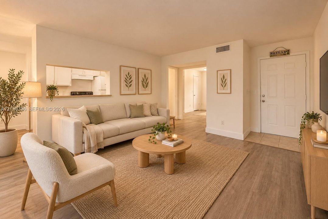 Living area featuring wood-finish flooring, a wall-mounted pass-through window to the kitchen, and a solid-core six-panel entry door