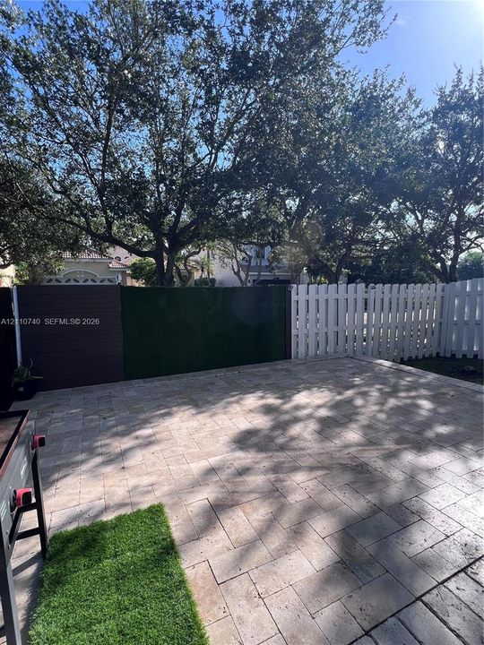 Backyard featuring a paved patio, privacy fencing, and mature trees