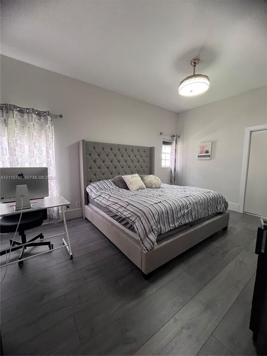 Wood-finish plank flooring, neutral wall tones, and overhead semi-flush mount lighting