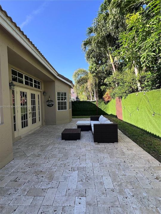 Paver patio featuring a herringbone pattern, double French door entrance with transom windows, and perimeter privacy fencing