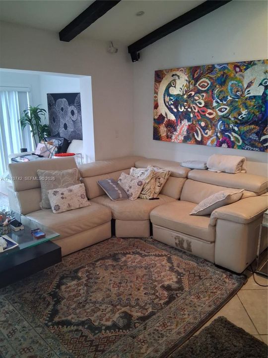 Vaulted ceiling featuring exposed dark-finish structural beams and tile flooring