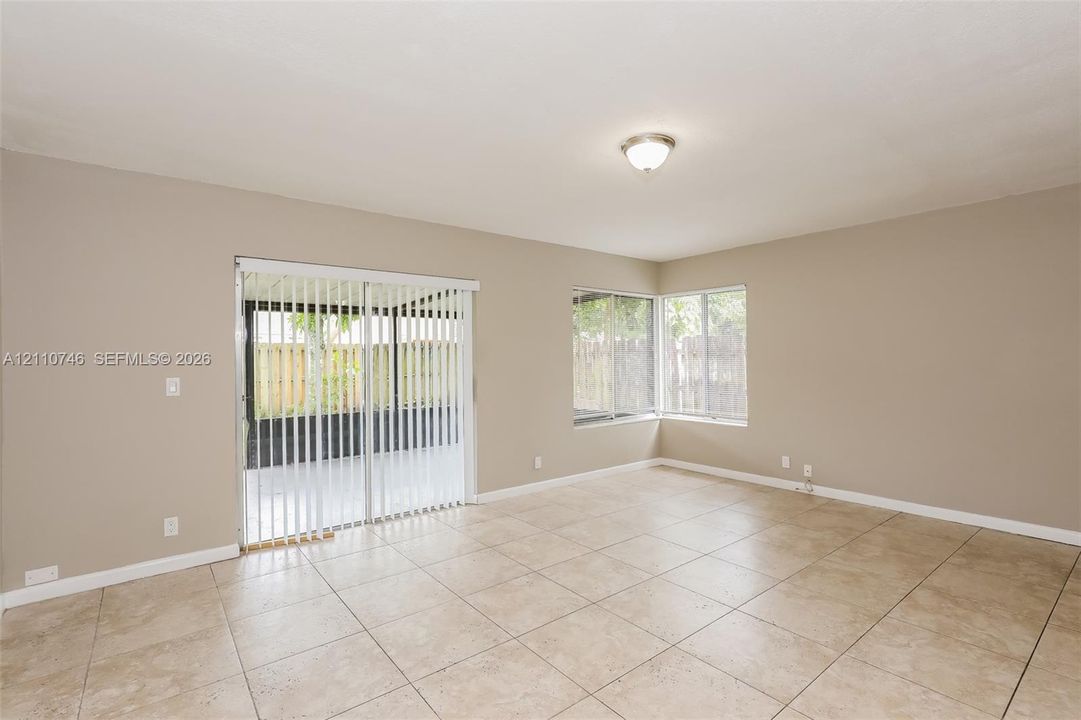 Interior space featuring tile flooring, sliding glass door with vertical blinds, dual windows, and flush-mount ceiling lighting