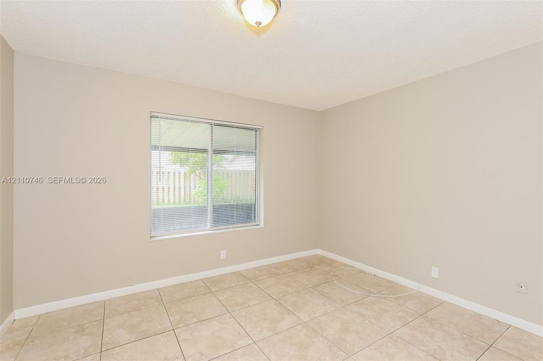 Neutral-toned interior space featuring light-colored tile flooring, a large sliding window, and a ceiling-mounted light fixture