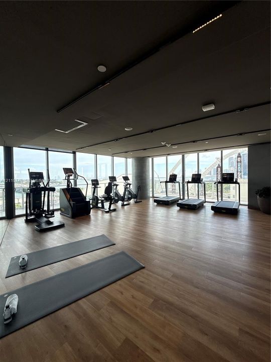 Fitness area featuring floor-to-ceiling windows, wood-finish flooring, and recessed ceiling lighting