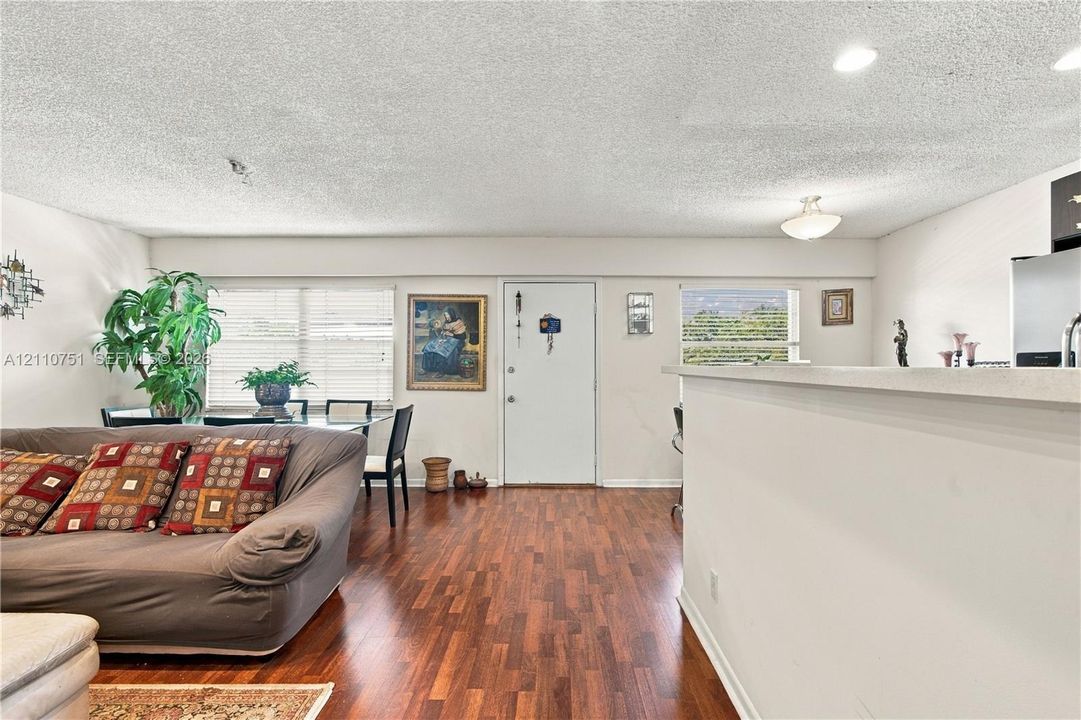 Open-concept interior featuring wood-finish flooring, recessed lighting, and a kitchen breakfast bar with stone-finish countertop