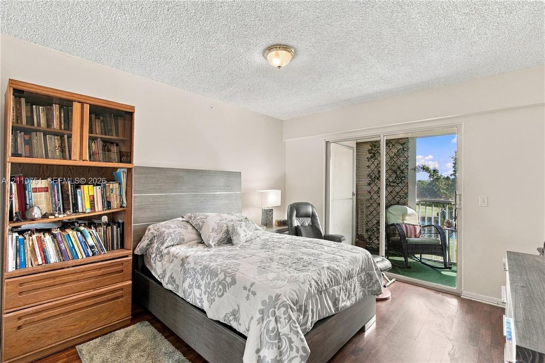 Room featuring wood-finish flooring, textured ceiling, flush-mount light fixture, and sliding glass doors providing outdoor access