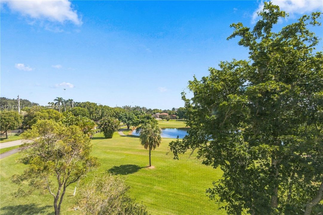 Expansive landscaped grounds featuring mature trees, a manicured lawn, and a natural pond