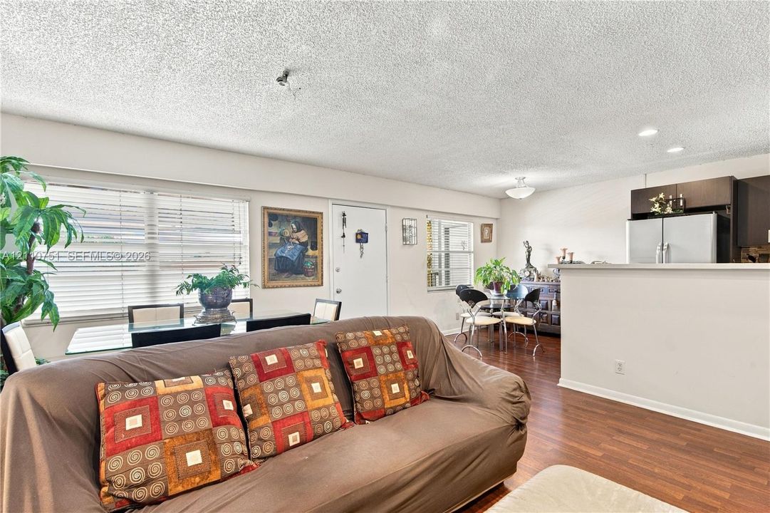 Open-concept living space featuring wood-finish flooring, horizontal window blinds, and recessed lighting