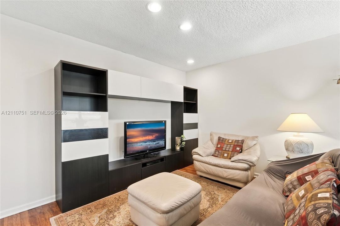Built-in high-contrast black and white cabinetry, recessed ceiling lighting, and wood-finish flooring
