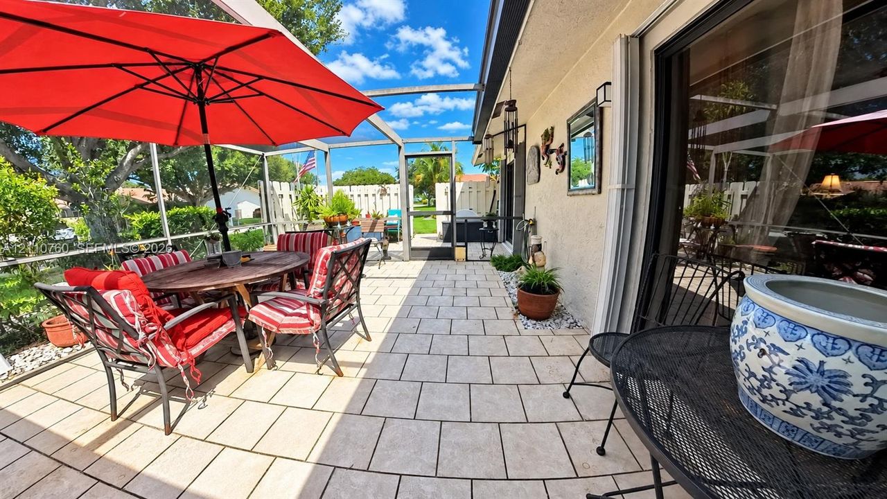 Screened-in lanai featuring light-toned tile flooring, stucco exterior wall, and sliding glass doors