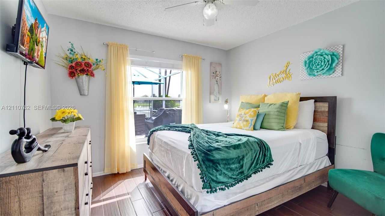 Wood-finish flooring, ceiling fan with integrated light fixture, and large window providing natural light