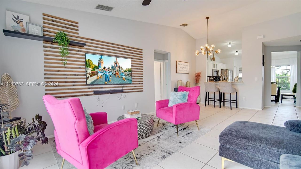 Living area featuring a horizontal wood-slat accent wall with a floating shelf, vaulted ceilings, and a multi-arm chandelier