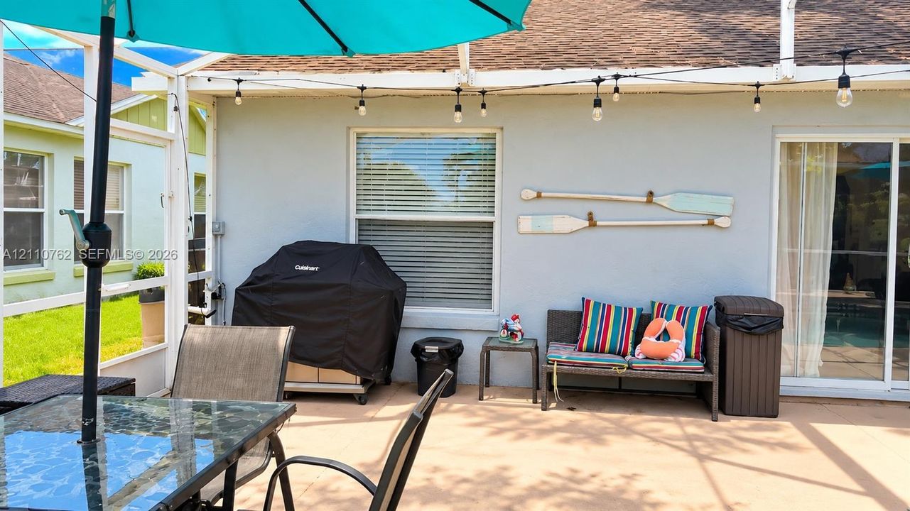 Screen-enclosed patio featuring a concrete floor, integrated overhead string lighting, and sliding glass door entry