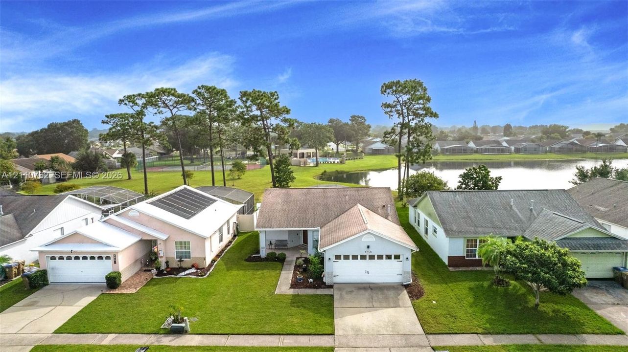 Single-story residence featuring a paved driveway, attached two-car garage, manicured lawn, and waterfront property positioning