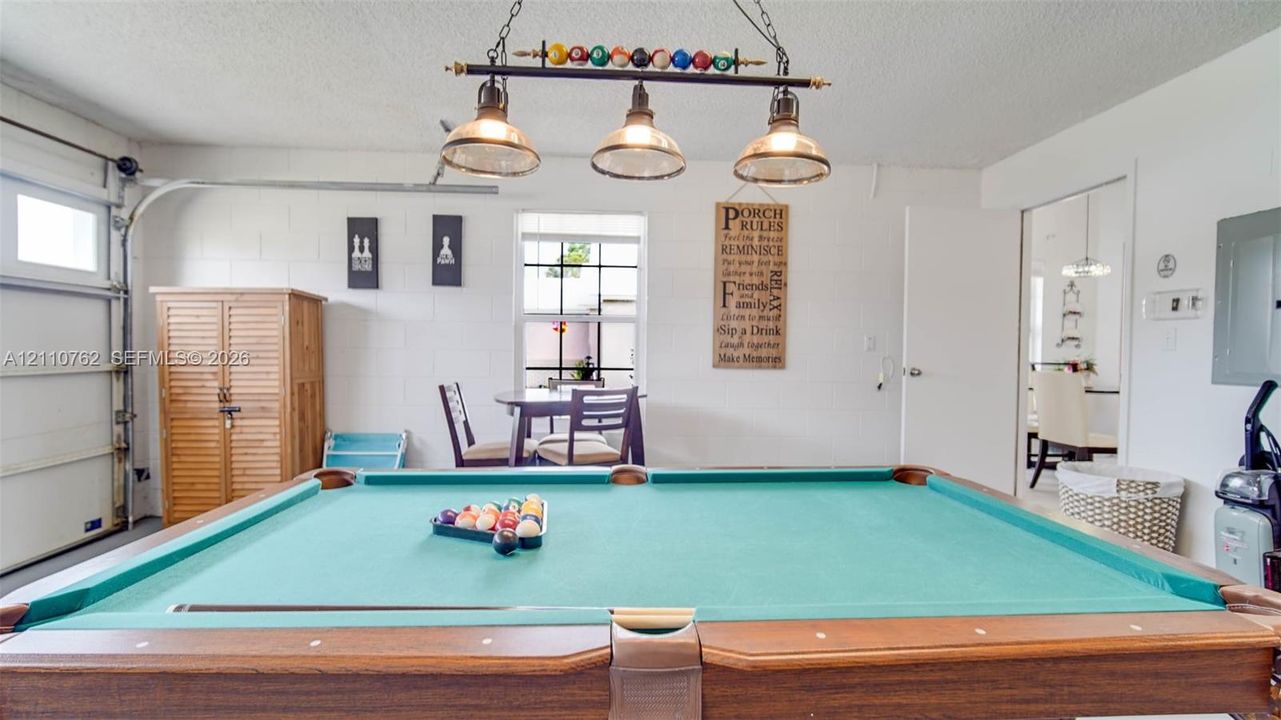 Multi-purpose space featuring a three-light metal billiard fixture, concrete block walls, and a single-pane window
