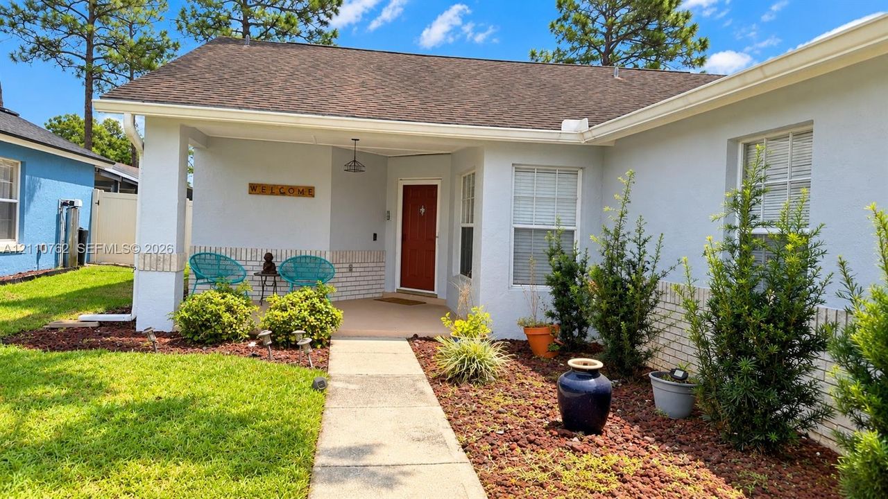 Covered front entryway featuring a painted exterior, brick facade accents, and a concrete walkway