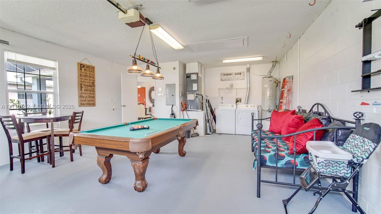 Multi-use garage space featuring painted concrete flooring, exposed block walls, recessed lighting, and dedicated laundry area with utility hookups